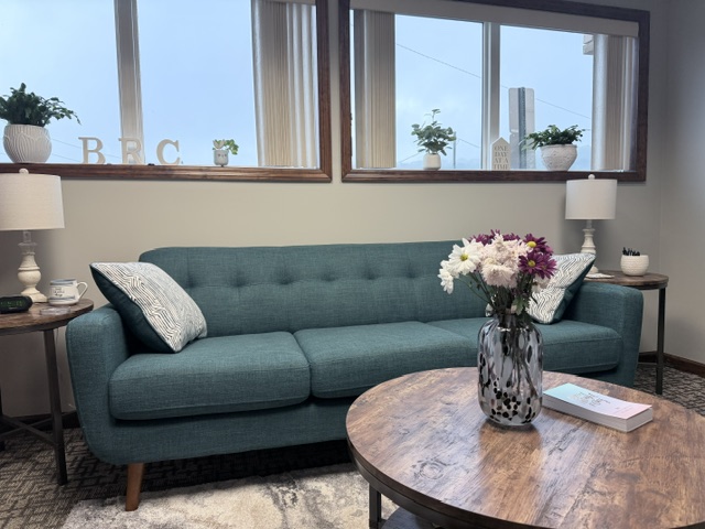 The calm Blooming Roads Counseling office with a welcoming teal sofa and flowers