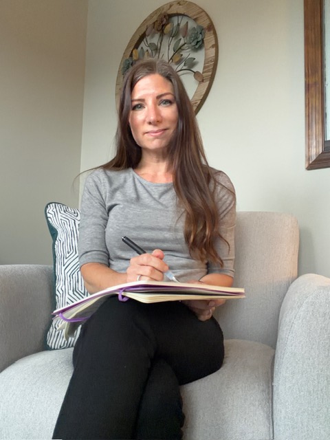 Lisa Medvetz seated with a notebook in the Blooming Roads Counseling office