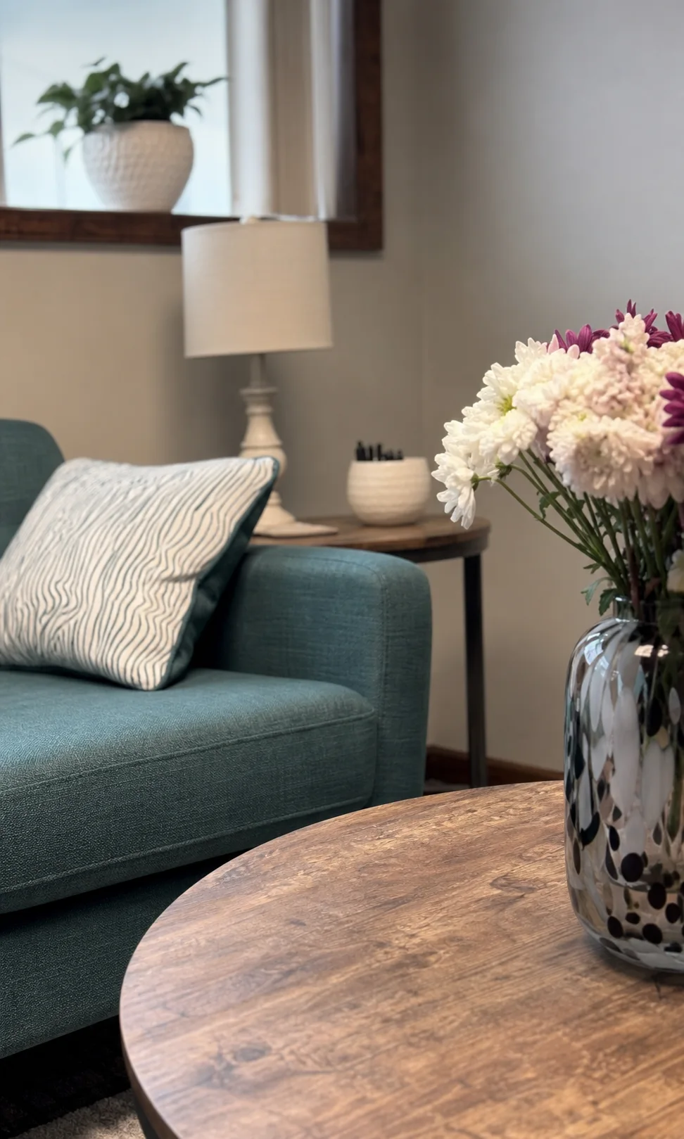 A close view of the teal sofa, flowers, and warm wood in the Blooming Roads office